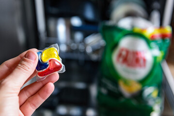 Woman putting detergent capsule into dishwasher.