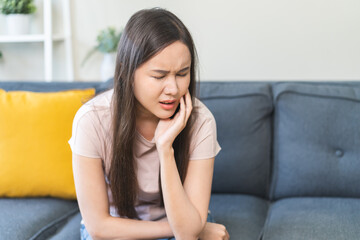 Obraz premium Sensitive teeth, health care concept. Teeth pain and dentistry asian young woman suffer touching her cheek. Female feeling painful toothache. Unhappy feel bad, diseases in oral, ache nerve and molar.