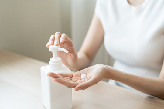 Healthy skin care,beauty asian young woman in bathrobe after shower bath at home, squeeze out moisturizer from bottle, putting on her hand. Skin body cream moisturizing lotion, routine in the morning