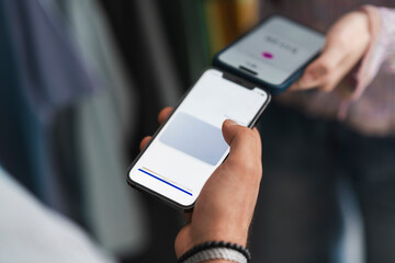 A person holds a smartphone displaying a digital vaccination pass, while another person holds a phone with a payment app open, suggesting a contactless transaction.