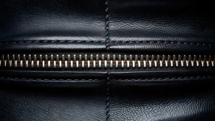 Close up of a luxurious navy blue leather texture with a polished metal zipper and detailed stitching exuding sophistication