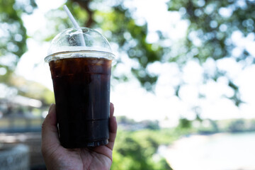 Iced Americano in plastic cup against nature background
