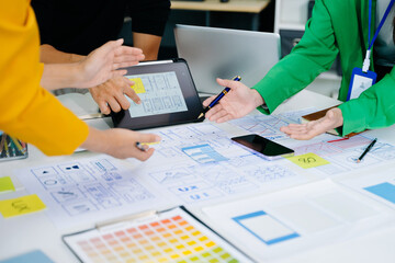 UX developer and ui designer brainstorming about mobile app interface wireframe design with customer breif and color code at modern office.