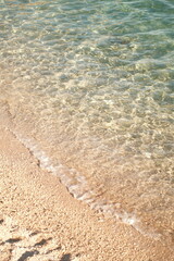 Clear turquoise water gently lapping against sandy beach creating a serene coastal atmosphere