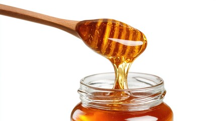 Golden honey dripping from wooden dipper into glass jar on white background, natural sweet organic food product