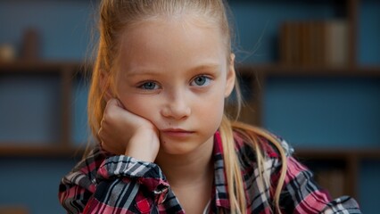 Portrait Caucasian little boring child girl kid daughter looking at camera sad upset at evening...