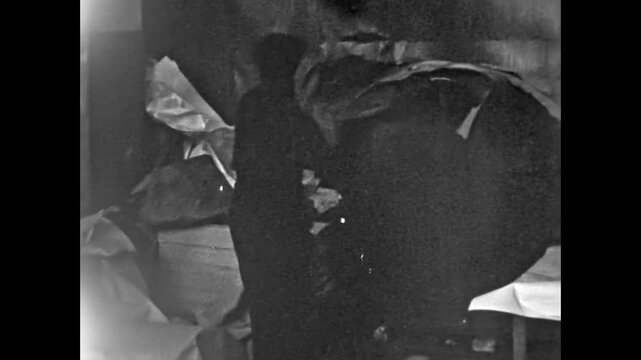 Vintage film, Paper recycling, man stacking paper waste piles at factory indoors. Manufacturing paper material industry. Manual labor in recycling work. Old archive video. Archival retro 1960s