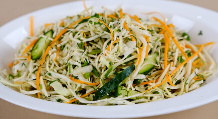 Fresh salad of white cabbage with carrots dressed with olive oil close-up in a bowl on the table. Vertical top view from above . High quality photo
