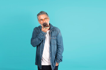 Senior man dictating voice message on smartphone thinking