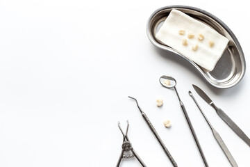 Many dental metal tools and teeth crowns in tray for dental implantation on white background. Professional Dentist tools, top view