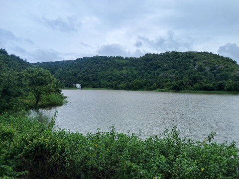 Lush Green Hillside Landscape Reflected on Calm Reservoir Water. Beautiful view of Purulia with its beautiful mountains on a rainy day.