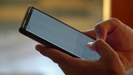 Close up video of man typing on smartphone using both hands in natural light. Concept of communication, messaging, technology, and everyday lifestyle - Powered by Adobe