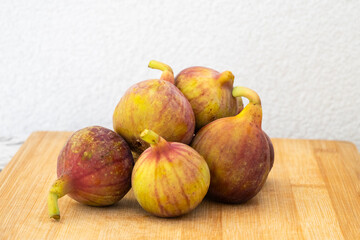 Ripe figs  rest on a wooden cutting board, bathed in soft indoor light.