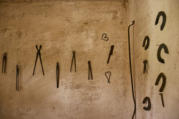 Set of blacksmith tools and horseshoe on the wall of the forge. Ancient blacksmith tools. Traditional blacksmithing. Decoration on the wall of the forge.