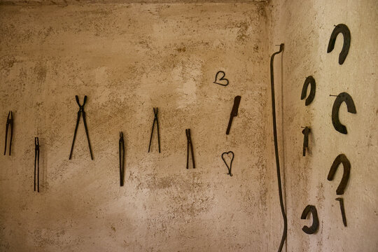 Set of blacksmith tools and horseshoe on the wall of the forge. Ancient blacksmith tools. Traditional blacksmithing. Decoration on the wall of the forge.