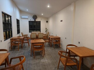 Minimalist café interior with wooden tables and chairs under warm lighting, creating a cozy and modern atmosphere. Perfect for design inspiration, restaurant marketing, or property promotion.