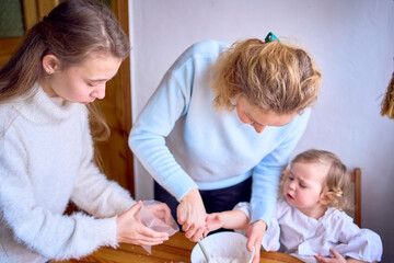 mother and a cranky toddler are cooking cream for a Christmas gingerbread house in the kitchen