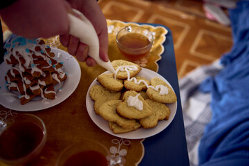 family with daughters toddler and teenager cozy together drinking tea and eating gingerbread Christmas tree