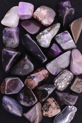 Sugilite heap jewel stones texture background. Pile mineral pebbles backdrop.
