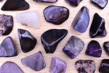 Sugilite rare jewel stones on light varnished wood texture. Sparse mineral pebbles background.