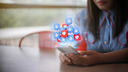 A woman's hands holding a smartphone with holographic social media icons for likes and hearts, symbolizing engagement and online communication in the digital marketing era.