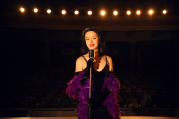 Woman singing on stage in vintage style with a retro microphone and dramatic lighting