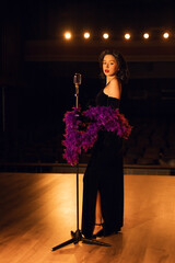 Woman singing on stage in vintage style with a retro microphone and dramatic lighting
