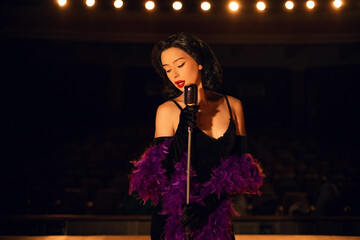 Woman singing on stage in vintage style with a retro microphone and dramatic lighting