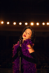 Woman singing on stage in vintage style with a retro microphone and dramatic lighting