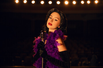 Woman singing on stage in vintage style with a retro microphone and dramatic lighting