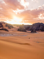 Landscape of the Red Tadrart with dunes and rock formations at sunrise in the Sahara Desert, Algeria.