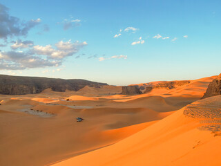 Landscape of the Red Tadrart with dunes and rock formations at sunrise in the Sahara Desert, Algeria.