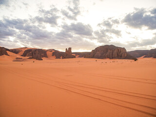 Landscape of the Red Tadrart with dunes and rock formations at sunrise in the Sahara Desert, Algeria.