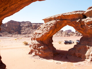 Desert landscape of the Red Tadrart with rock formations and golden sand under a blue sky. Natural scenery of the Algerian Sahara.