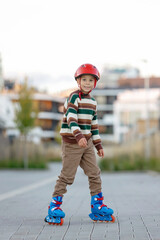 Fototapeta premium Cute school child, boy, riding roller skates, skating on the street autumn