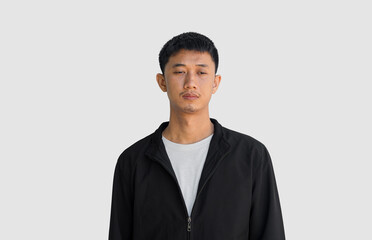 A young Asian man in his 20s wearing black coat is depressed and worried in distress standing on a grey background. Crying in anger and fear. Sad expression concept