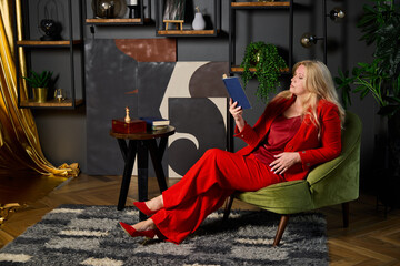 Obraz premium stylish lady enjoying tea and book, chic woman in red attire relaxing with reading material and tea