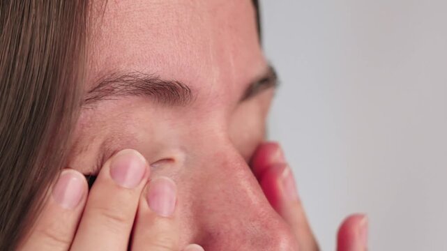 Close-up of a woman rubbing eyes with her hands, concept of tiredness, overworked, dryness or allergy.
