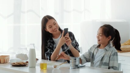 A mother and daughter enjoy precious time together in the kitchen, cooking and laughing. The bright space is filled with ingredients, emphasizing love and bonding during family activities.