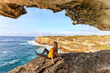 Woman relaxing by the ocean in a sandstone cave