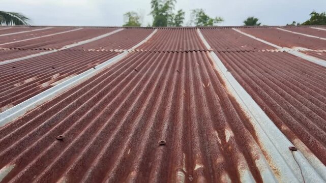 A close-up view of an old rusty zinc roof showing textures of corrosion and weathered metal. The pattern of rust and decay.
