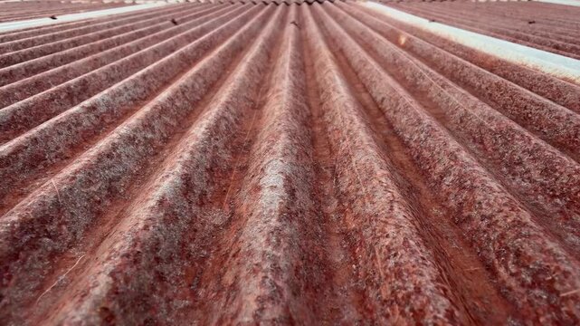 A close-up view of an old rusty zinc roof showing textures of corrosion and weathered metal. The pattern of rust and decay.