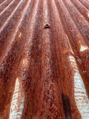 Close-up view of an old rusty zinc roof showing textures of corrosion and weathered metal. The pattern of rust and decay.