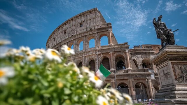 Ancient roman colosseum under bright blue sky with statue and flowers
