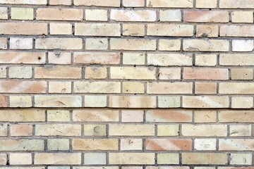 Obraz premium Close-up of a light beige brick wall texture showing weathered surfaces and grout lines perfect for architectural backgrounds and design elements