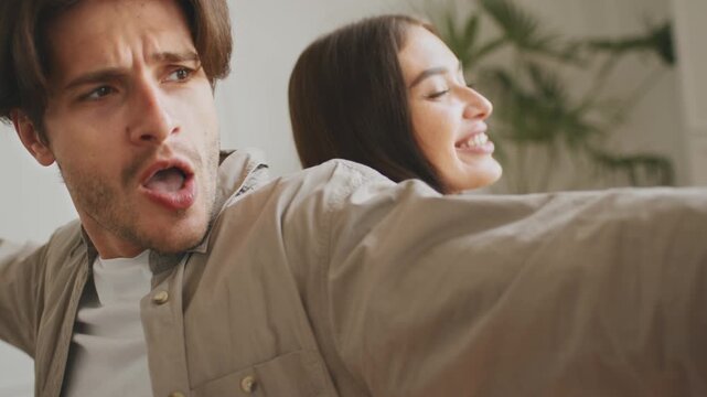 A couple is joyfully celebrating as they organize their belongings in their new apartment. Laughter fills the air, showcasing their excitement about moving and starting a fresh chapter together.