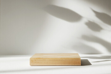 Natural wooden stand on white background. Mock up 3d empty podium for organic cosmetic product. Abstract studio background with shadows of window. Empty 3d room. Display product with blurred backdrop.