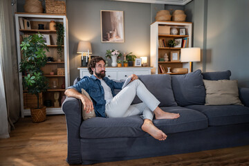 Obraz premium Man relaxing on cozy couch watching tablet