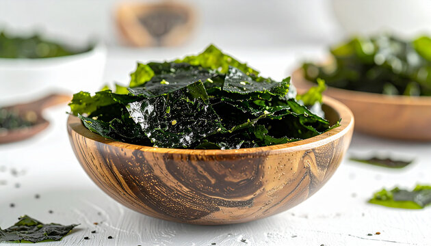 Green nori seaweed flakes in wooden bowl on white tabletop, soft natural lighting