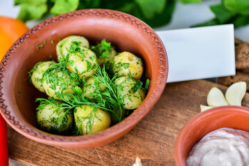 boiled potatoes with dill in a clay plate on a table with food decor